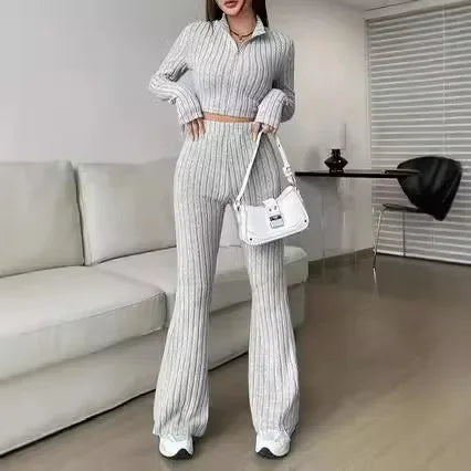 Striped 2-piece women's set in light gray with a zip-up crop top and flared pants, accessorized with a white handbag for casual elegance.