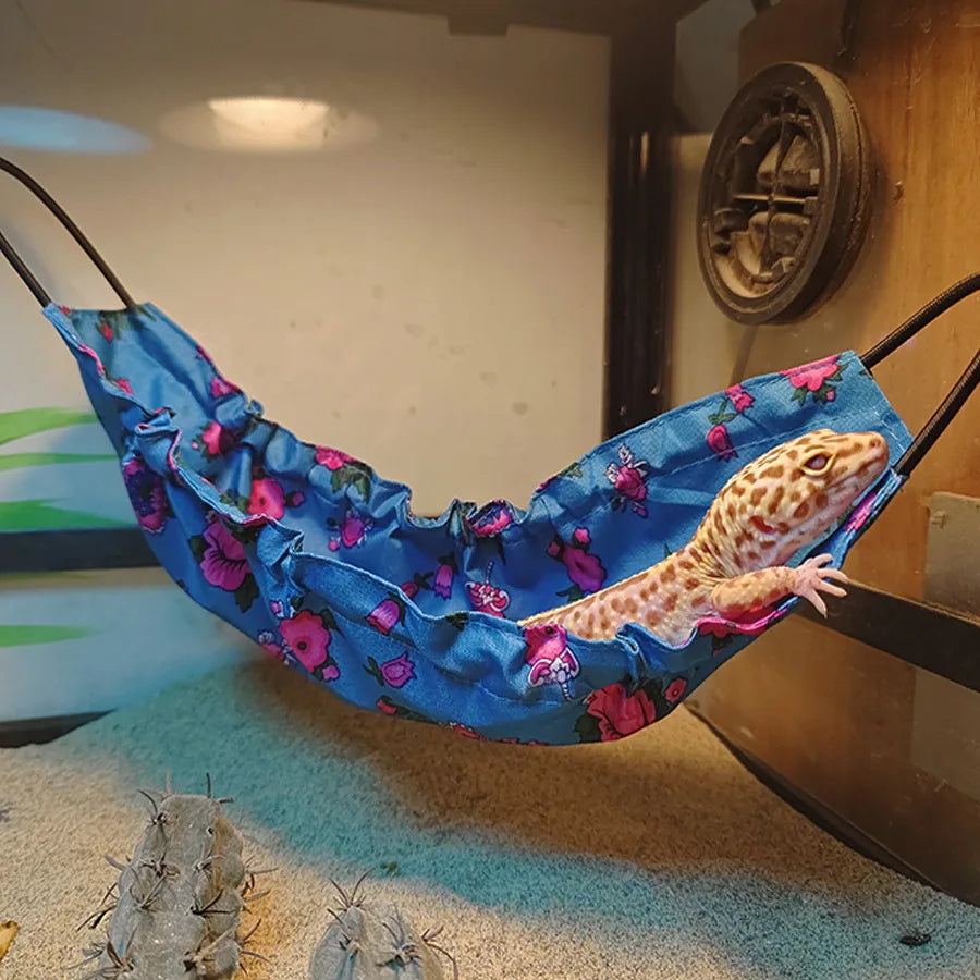 Leopard gecko climbing out of a blue floral Lizard Climbing Hammock, a decorative and cozy pet hideaway for reptiles.