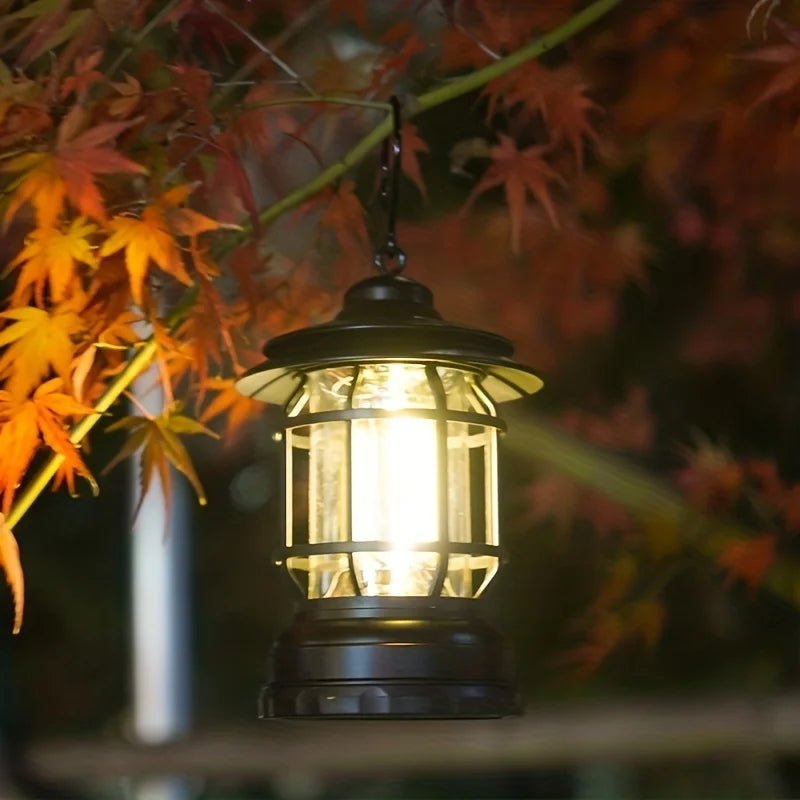 Vintage-style LED camping light hanging from a tree, illuminating a campsite with warm white light for outdoor adventures.