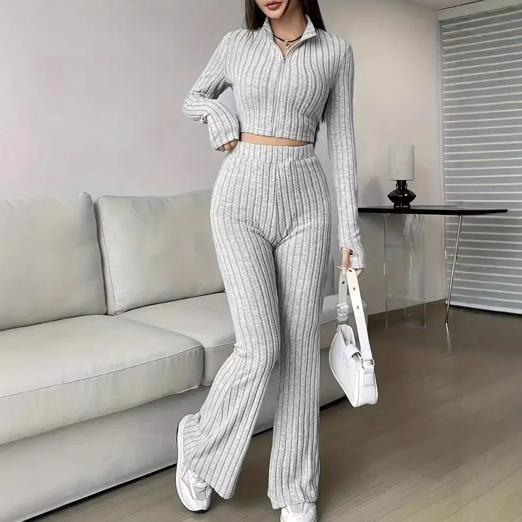 Gray striped 2-piece women's casual set with ribbed crop top and flared pants, styled with white sneakers and handbag for a chic look.