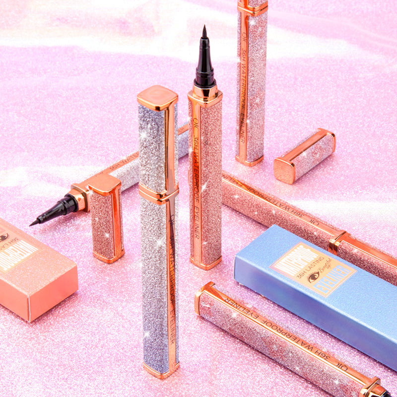 Galaxy Waterproof Eyeliner Pens displayed on pink glitter surface with open caps, emphasizing luxury design and long-lasting formula.