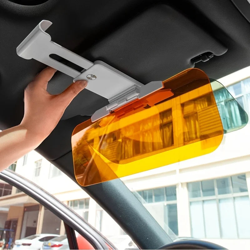 Hand adjusting the dual-panel car sun visor glare shield mounted on a vehicle's interior roof, featuring yellow and gray glare-reducing panels.
